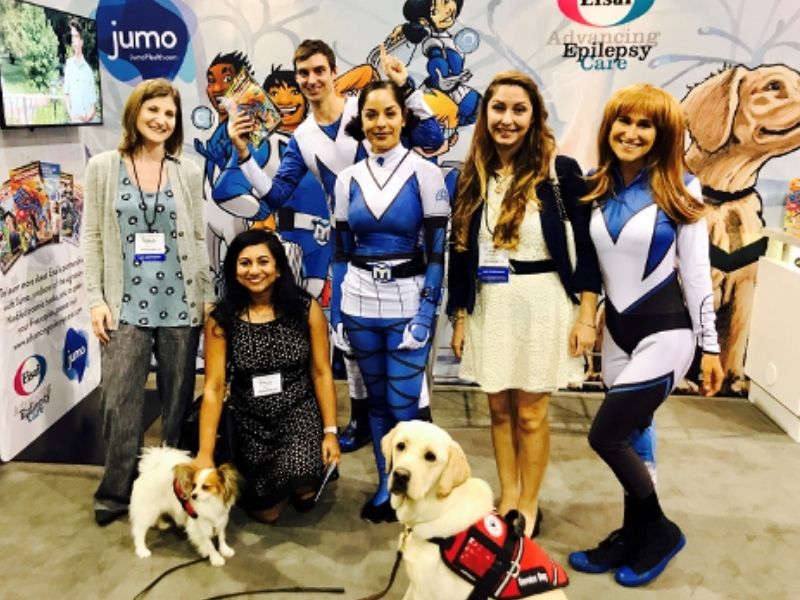 Student stand with service dogs handled by people dressed as super heroes.